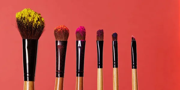 Makeup brushes, everyday make-up tools. Cosmetic essentials on bright blue background, closeup