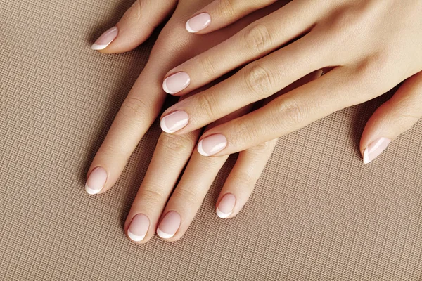 Jovem Palma Feminina. Bonita manicura glamour. Estilo francês. Verniz nas unhas. Cuidados com as mãos e unhas, pele limpa — Fotografia de Stock