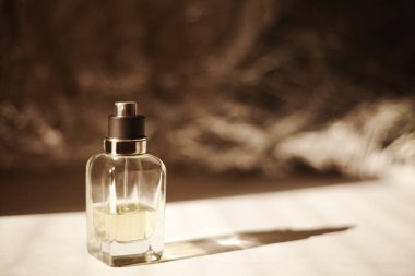 Bir şişe parfüm doldurulmuş. Arka planda gölgeler ve ışık. Mükemmel ibnelik. Güçlü gölgeler