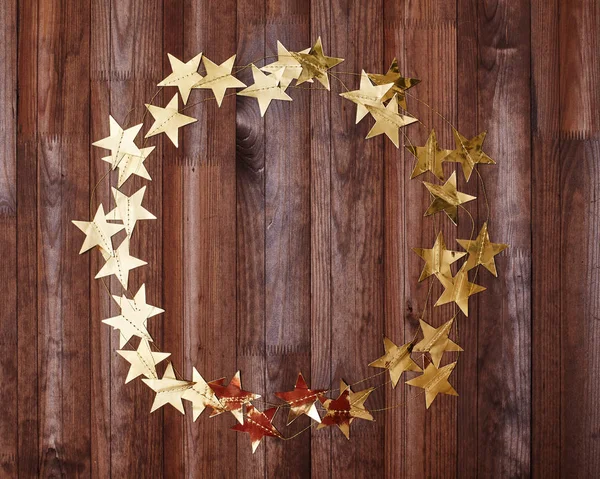 Party Mockup Round Gold Stars Frame on Dark Wood. Christmas Shiny Golden Tinsel for Card Design with Copy Space for Text