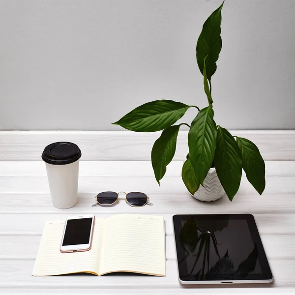 Minimální pracovní stůl s tabletem, smartphonem, poznámkou a kávou. Kancelářský stůl na volné noze. Stylové pracoviště s příslušenstvím — Stock fotografie