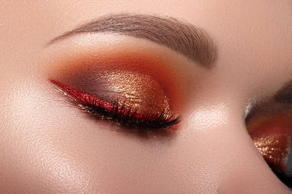 Fashion Celebrate Makeup with Red Liner, Gold Shadows, Glowy Clean Skin, perfect Shapes of Brows. Macro of Female Eye — kuvapankkivalokuva