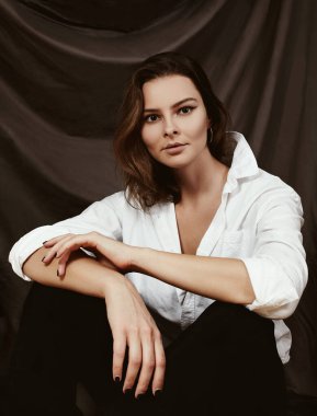 Çekici Genç Kadın Beyaz Gömlekli Poz Veriyor. Moda Dişi Günlük Tarzı. Kumaş Arkaplanda Klasik Portre