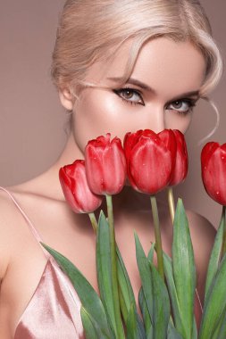 Lüks retro makyajlı güzel, seksi sarışın kadın. Bahar Çiçekleri Buketi olan bir kız her kutlama için bej arka planda. Kadınlar Günü ya da Sevgililer Günü için Taze Tarz