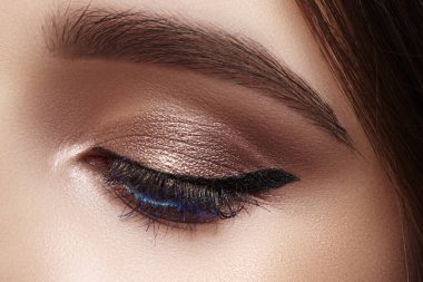 Klasik göz kalemi makyajlı güzel bir makro kadın gözü. Mükemmel kaşlar, kahverengi göz farı ve uzun kirpikleri. Makyaj malzemeleri ve makyaj malzemeleri. Moda gemisi bakışlarının yakın çekim makro çekimi.