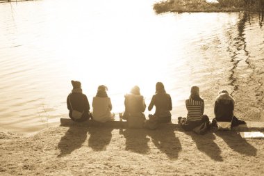 bir göl yanında oturan insanlar