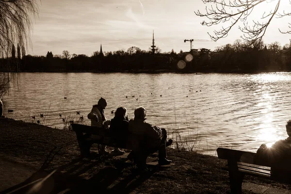 Persone sedute vicino al lago — Foto Stock