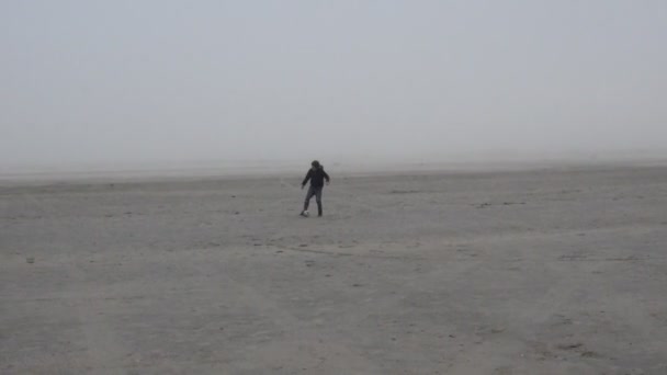 Menino jogando bola na praia em nevoeiro — Vídeo de Stock