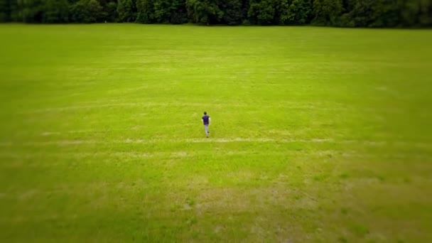 Jonge man loopt snel op een groen veld — Stockvideo