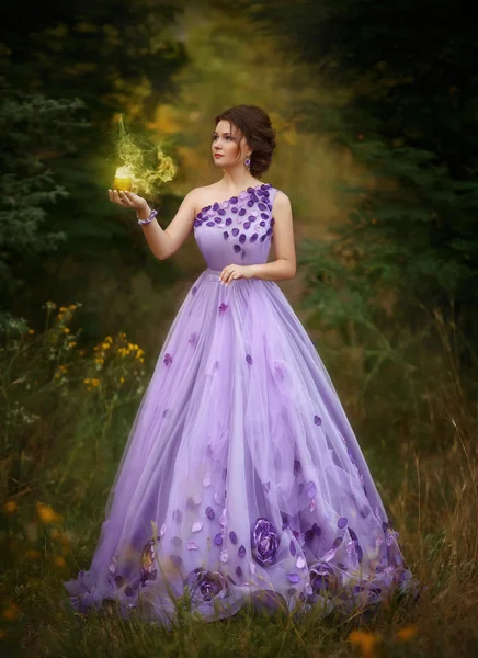 Krásná dívka v nádherné fialové dlouhé šaty, drží svíčku — Stock fotografie