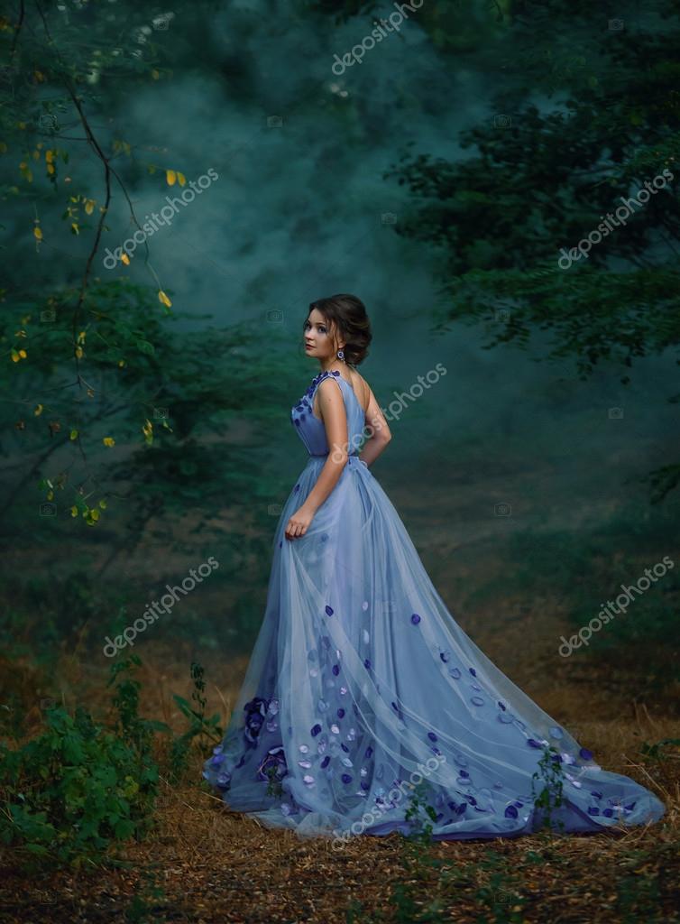 Girl in a long dress wandering the forest in the fog Stock Photo
