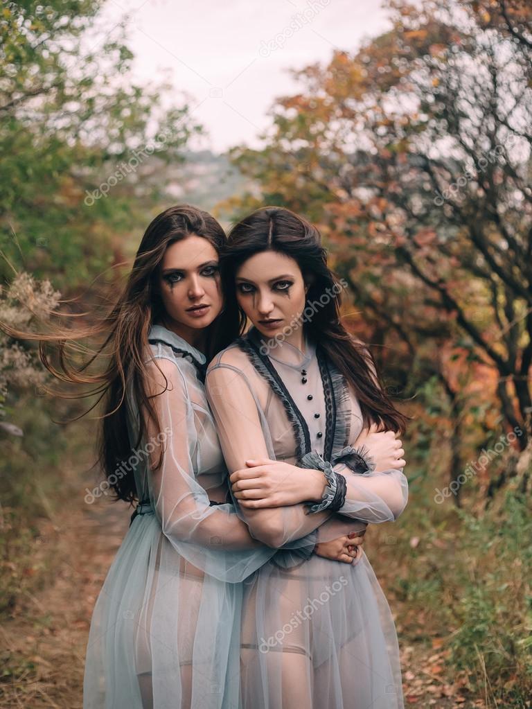 Two terrible lady in long white dresses hugging each other Stock
