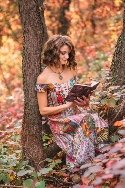 Bir kitap ile bir ağacın altında oturup genç güzel kız — Stok fotoğraf