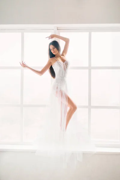 Розкішна сексуальна дівчина, вона танцює на підвіконні в білому світлі — стокове фото