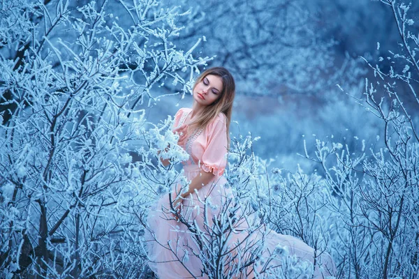 O karlı dalları arasında oturan güzel genç kız. — Stok fotoğraf