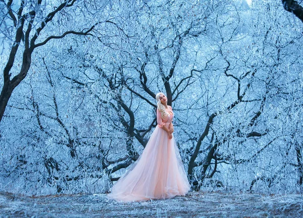 Schöne junge Mädchen steht eins unter schneebedeckten Bäumen. — Stockfoto