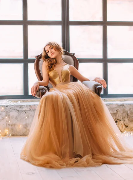 Das brünette Mädchen in einem luxuriösen, goldenen Kleid — Stockfoto