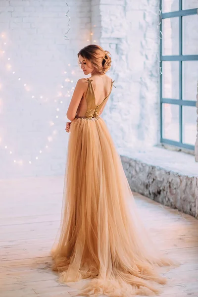 De brunette meisje in een luxe, gouden jurk — Stockfoto
