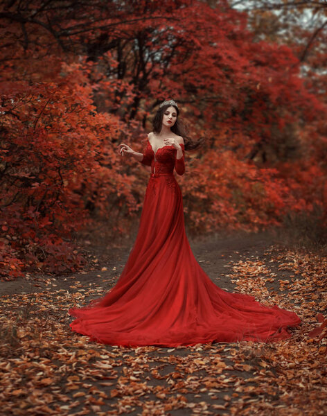Incredible stunning girl in a red dress. The background is fantastic autumn. Artistic photography.