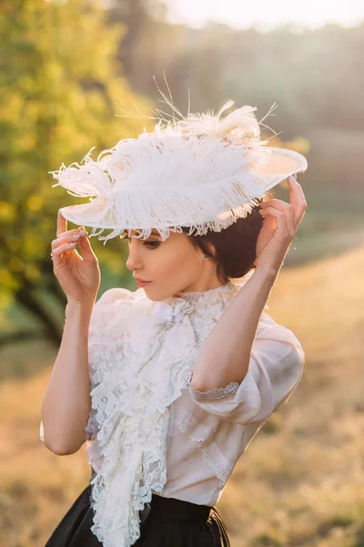 모자에 빈티지 드레스에 아가씨 자연의 배경에 사이에서 걷는다 — 스톡 사진