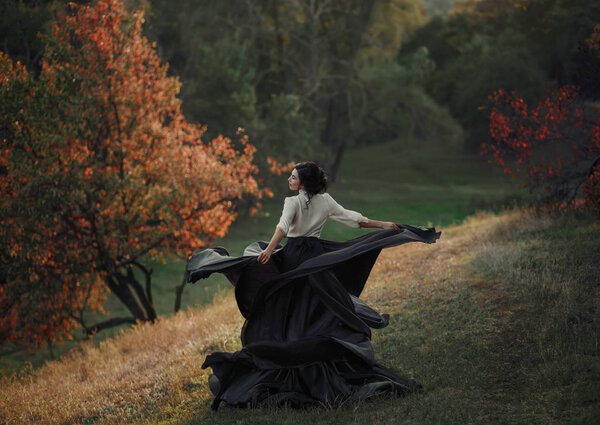 A girl in a vintage dress is spinning on a hill. Background wild nature. Taste of freedom. Artistic Photography