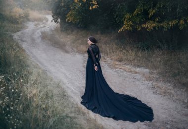 Eski korku filmlerindeki gotik kadın. Sonbahar ormanlarında yol boyunca yürür.