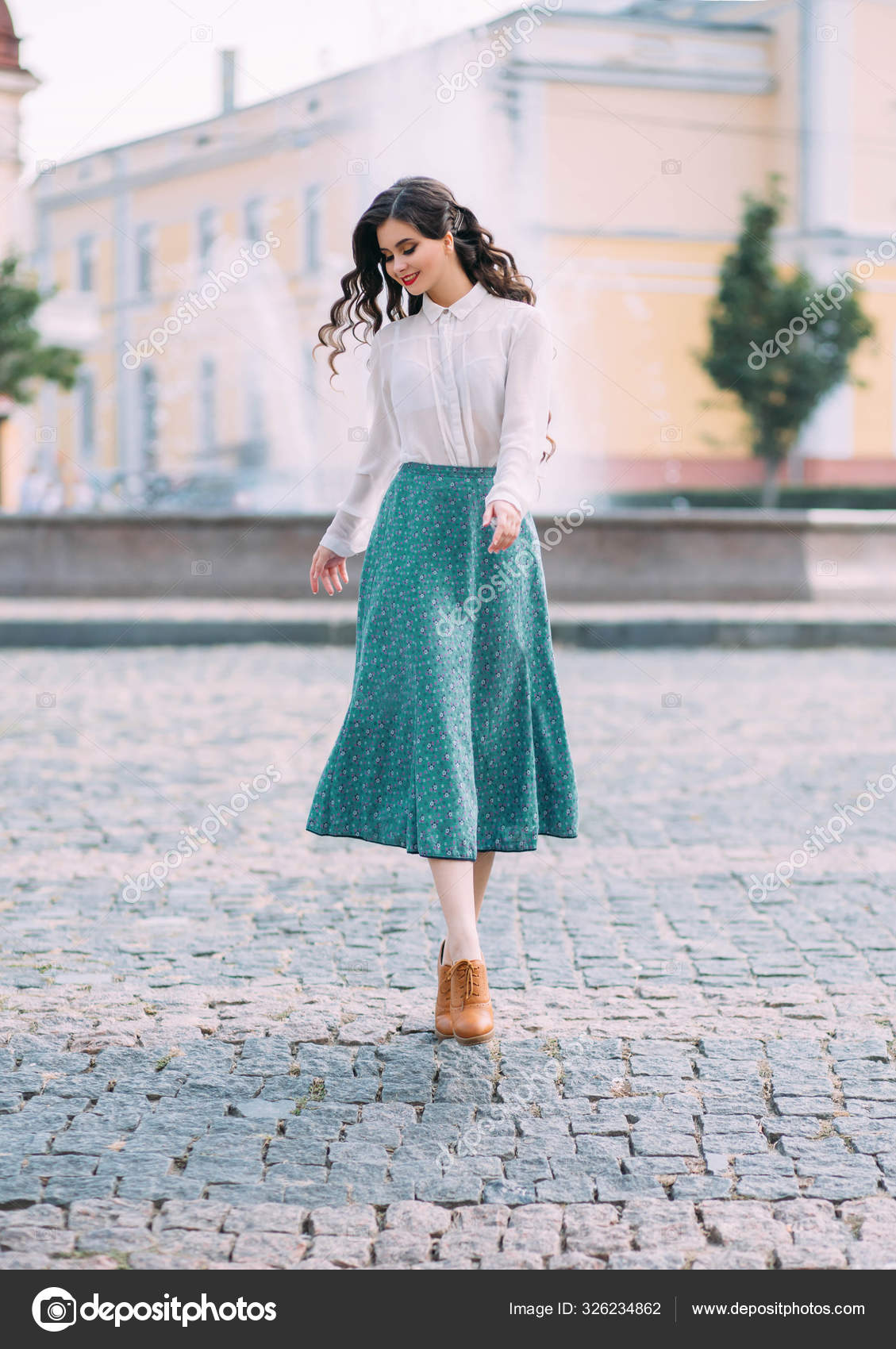 Woman brunette student is walking around street city outdoors. Long wavy hair flying in motion. cheerful happy girl. face smile. white vintage blouse, mint midi skirt brown retro boots. floral print Stock Woman brunette student is walking around street city outdoors. Long wavy hair flying in motion. cheerful happy girl. face smile. white vintage blouse, mint midi skirt brown retro boots. floral print Stock