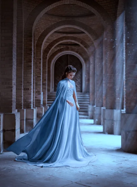 Sad Snow Queen walks in old castle. blue silk long raincoat train flying motion. Elven hairstyle cute face. Vintage fantasy art retro style. Frozen Fabulous woman photo shoot. sun magic shine rays — Stock Photo, Image