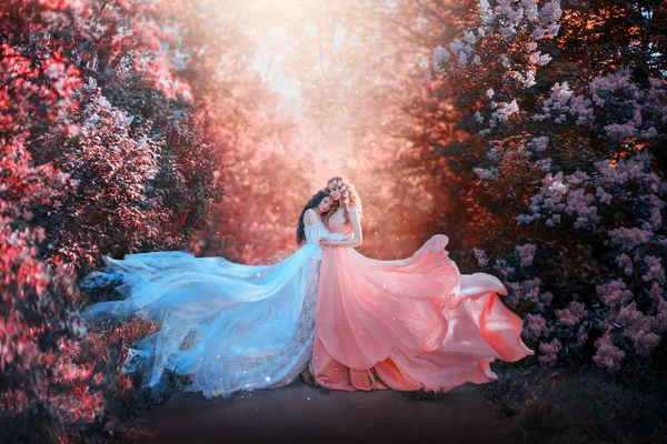 Uzun elbiseli iki kadın tren sineklerine sarılıyor. parlak mor renkler sanat rötuş işleme. Doğal kozmetik kokulu bahar çiçekleri hassasiyet parfüm kokusu. Sarışın, esmer. — Stok fotoğraf