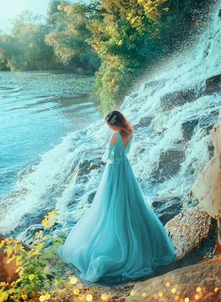 Elfe fille tourné dos ouvert debout sur la rive du lac. pierre éclaboussure d'eau. Automne d'été doré. Cheveux roux recueilli fleurs décorées. robe longue soirée turquoise bleue luxuriante. diplôme fête ballon art — Photo