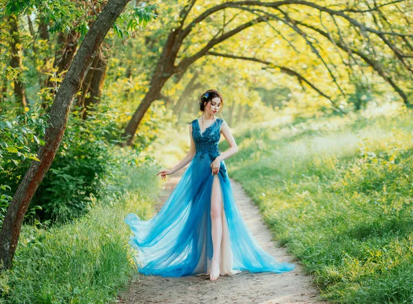 Одинокая сексуальная девушка голая нога ходить листву зеленый лес вечернее шикарное платье. волосы украшены голубыми цветами кукурузы. Элегантная прическа брюнетки. Солнечный яркий день Природа летняя весенняя свадьба искусство — стоковое фото