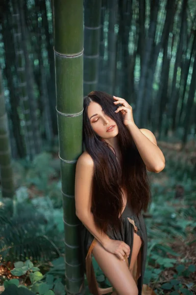 Amazônia muito sexy relaxar silêncio na floresta de bambu. mão tocar cabelos longos, olhos fechados. vestido de ninfa com decote profundo. arte pano de fundo verão trópicos natureza jardim botânico Geórgia. férias de primavera . — Fotografia de Stock