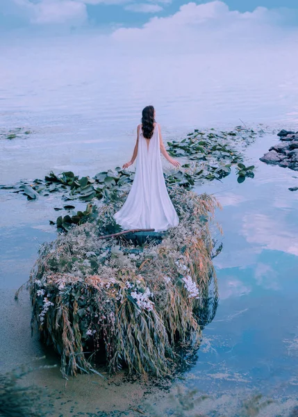 Şık, güzel, esmer prenses, çiçek desenli söğüt dallarıyla geri çevrilmiş bir sandalda duruyor. Trenli, beyaz, eski moda elbiseli bir kız. Yeşil gölün arka plan su yüzeyi nehir bitkilerini terk eder — Stok fotoğraf