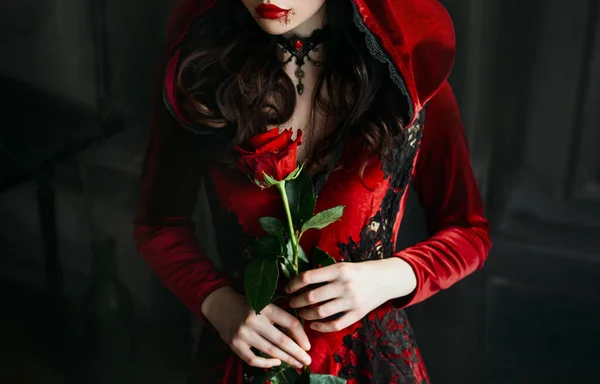 Junge Frau rote Kapuze. Vampirlippen tropfen Blut. Blutige Lippen halloween rose — Stockfoto