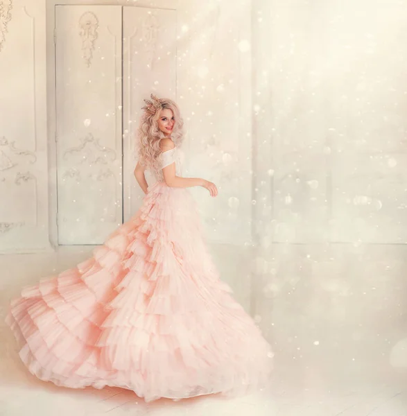 Happy young woman princess dancing in lush vintage pink dress. white royal room. Queen blond hair, golden crown. Light magic sparkles shiny. Carnival holiday invitation gesture. Background free space — Stock Photo, Image