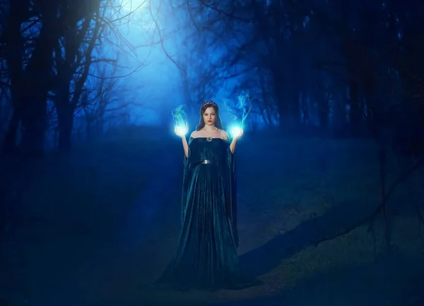 Mystic bellezza donna strega malvagia in notte buia nebbia foresta luce blu luna. Mani che bruciano incantesimo magico fuoco. Vampiro regina demone potere faccia. Vintage mantello abito medievale. spaventoso signora halloween stile vestiti — Foto Stock