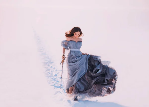 Fantasía princesa solitaria pelirroja elfo camina invierno helada blanca nieve naturaleza. La joven belleza corre. Reina sostiene las manos espada espada mágica. Vestido vintage largo de seda azul revoloteando viento mosca en movimiento — Foto de Stock