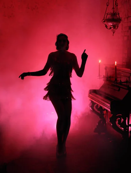Темный силуэт в стиле ретро в красном дыму. Девушка танцует в винтажном платье — стоковое фото