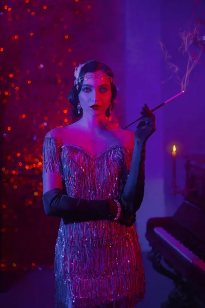 Portré flapper retro szépség divat modell nő dohányos. hosszú, vékony szájfeltétet tartva a kezében cigaretta égés. háttér klasszikus szoba füst. fotó neon kevert színes fény lila piros rózsaszín kék — Stock Fotó