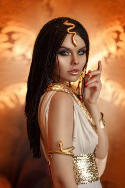 Kadın Kraliçe Kleopatra sanat fotoğrafı. Yaratıcı altın makyaj siyah saç örgüleri. Karnaval etnik Mısırlı kostüm elbisesi. Aksesuarlar, yılan bileziği tacı. Moda mankeni kız. Güzel yüz kaplaması.