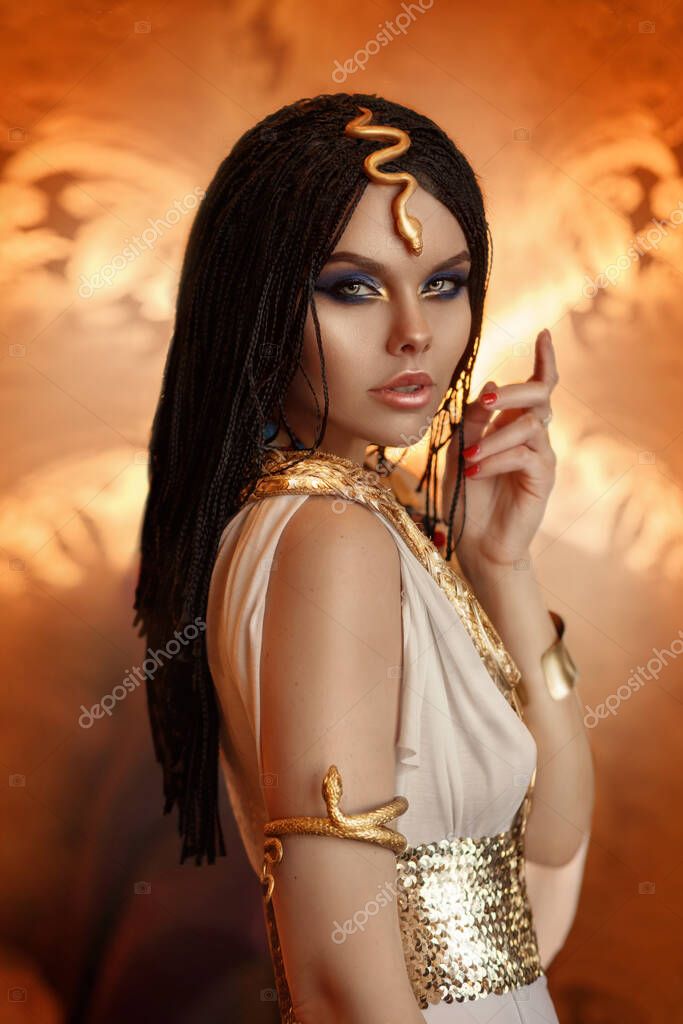 Donna regina Cleopatra foto d'arte. Trucco creativo dorato Trecce nere per  capelli. Abito da carnevale etnico egiziano. Accessori gioielli serpente  corona bracciale. Moda modella ragazza bel viso primo piano - Foto Stock
