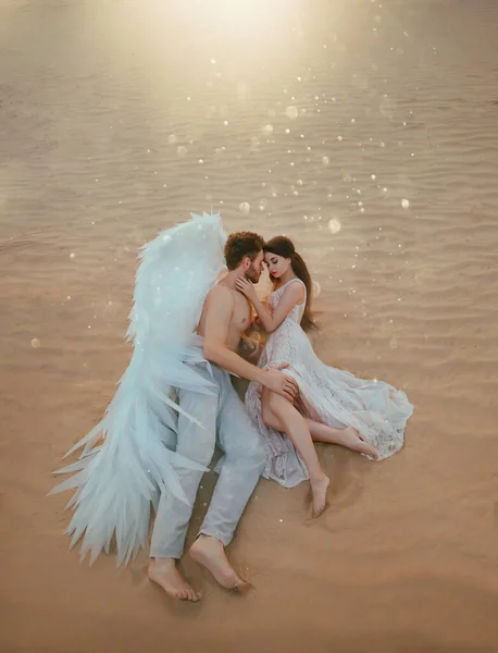 Artwork Men guardian angel protects and hugs, embrace young woman. beauty vintage pastel dress. miracle dream. Fabulous nature, sand desert . Divine light of love. Creative design white costume wings