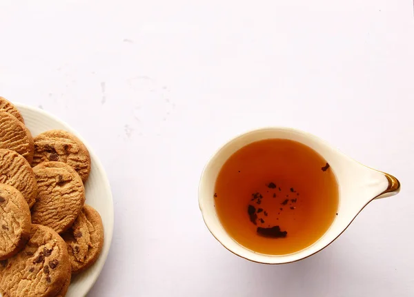 Schokoladenkekse und Tee auf weißem Hintergrund. — Stockfoto