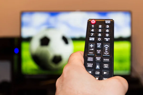 Смотря футбол / футбольную игру по современному телевидению, крупным планом — стоковое фото