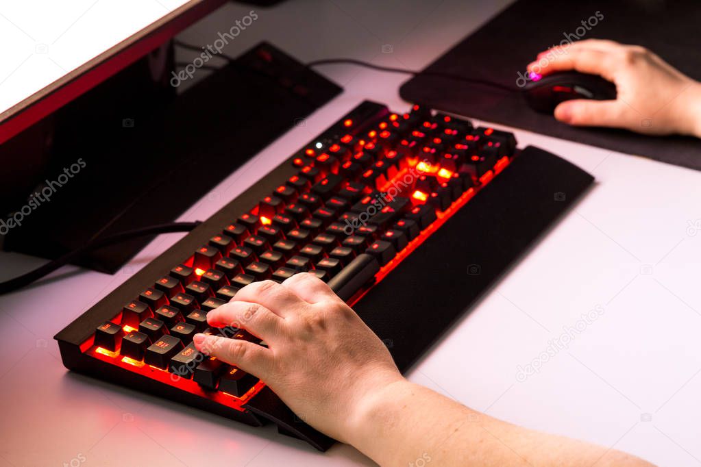 Female hands playing computer game with gaming gear.