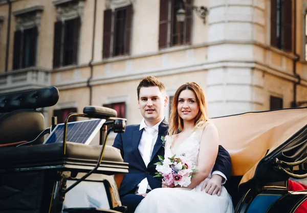 Glückliche Braut und Bräutigam in schöner Kutsche auf Hochzeitsmarsch — Stockfoto