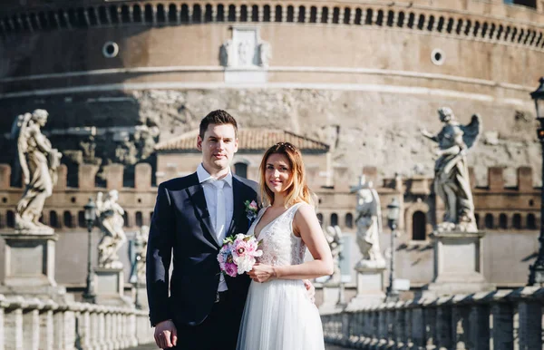 Novia y novio posan frente a Castel Sant 'Angelo, Ro —  Fotos de Stock