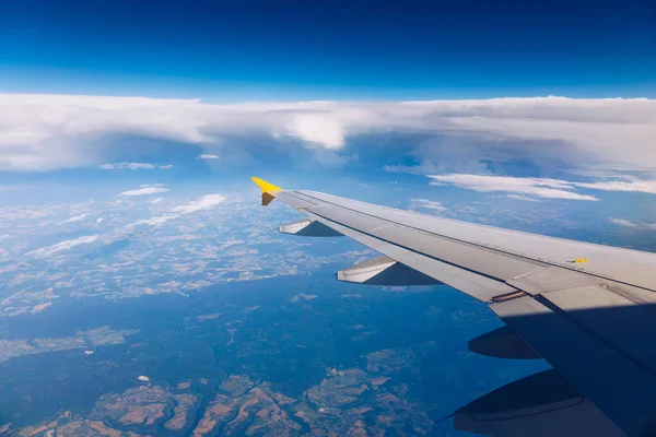 Uitzicht op de vleugel van een vliegtuig vliegen boven de wolken op hoge — Stockfoto