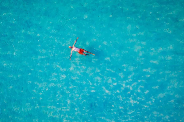 熱帯の海の水に浮かんでいる男のドローンビュー。空中風景 — ストック写真