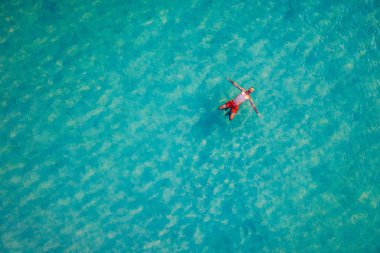 Drone view of a man floating in tropical sea water. Aerial view 